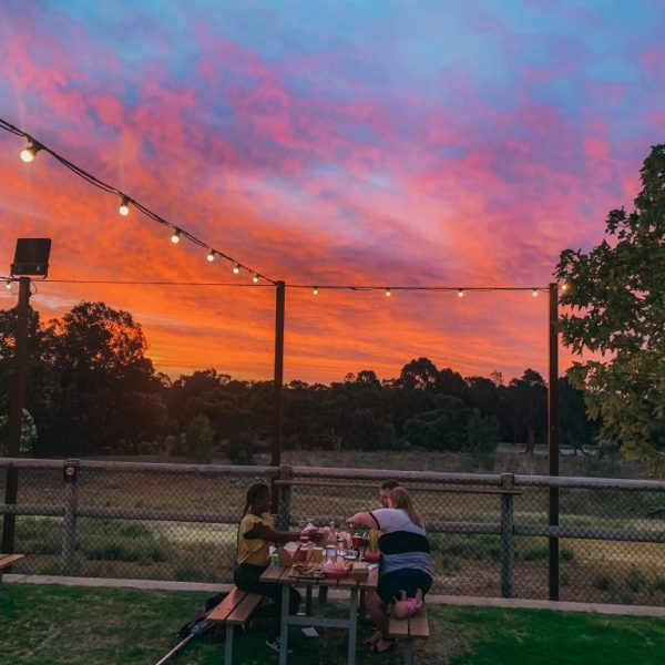 People dining outdoors at sunset