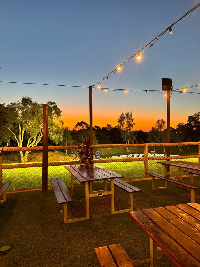 Outdoor picnic tables with string lights at sunset